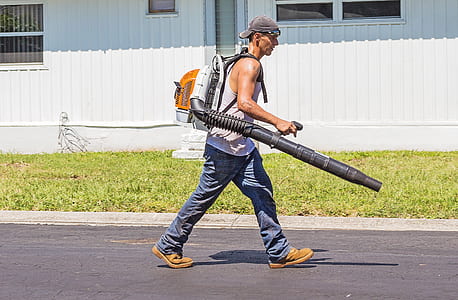 man carrying black and white leaf blower thumbnail