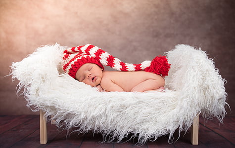 baby sleeping on white fur bed thumbnail