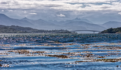 photo of a body of water with mountains  and bridge thumbnail