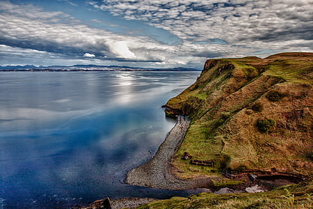 green and brown cliff over body of water during daytime thumbnail