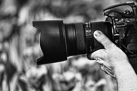 grayscale photograhy of person taking photo using DSLR camera thumbnail