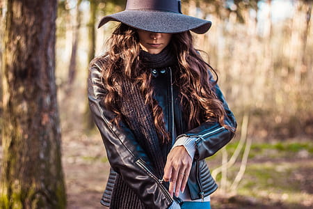 woman wearing black leather jacket zipping her jacket near trees thumbnail