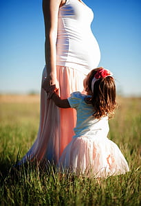 child standing next to woman in white top and pink skirt thumbnail