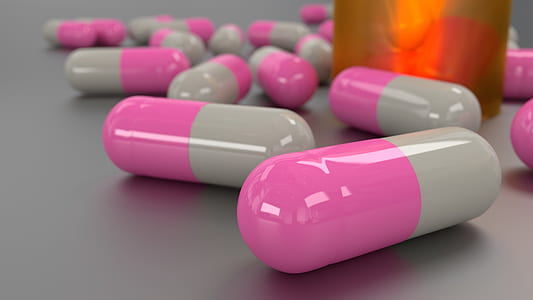 pink medication pills on gray floor thumbnail