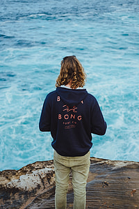 person standing on cliff facing body of water thumbnail