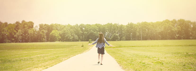 woman standing on pathway between green grass field during daytime thumbnail