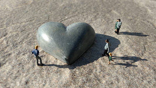 heart shaped gray stone surrounded by people figurines thumbnail