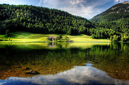 body of water beside mountain surrounding by trees thumbnail