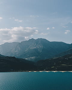 body of water near mountain at daytime thumbnail