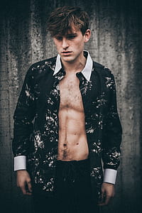 low light photography of man standing in front of concrete wall thumbnail