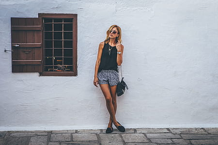 woman in black sleeveless top standing in front of white wall thumbnail