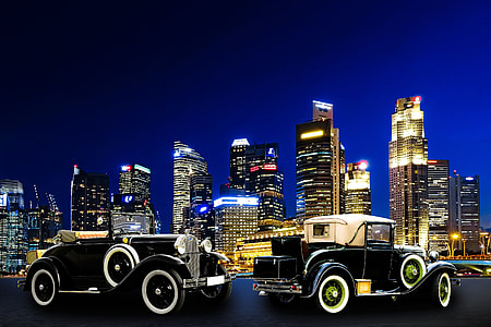 two vintage coupes near high-rise buildings taken during night time thumbnail