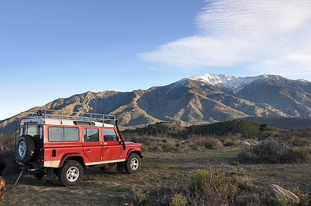 red and white SUV parked near mountain range thumbnail