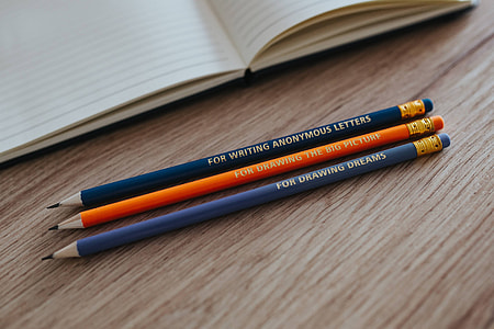 Notebooks with colourful pencils on a wooden desk thumbnail