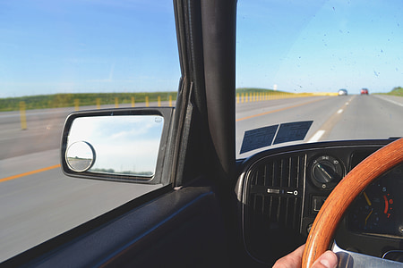 person riding inside vehicle passes on asphalt road thumbnail