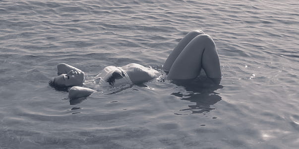 person in white bikini lying on body of water thumbnail