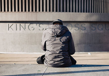 man sitting on pavement facing wall thumbnail