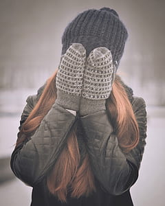 woman covering her face wearing winter gloves thumbnail