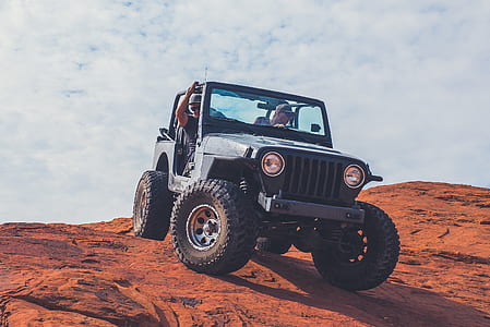 black Jeep Wrangler on brown sand thumbnail