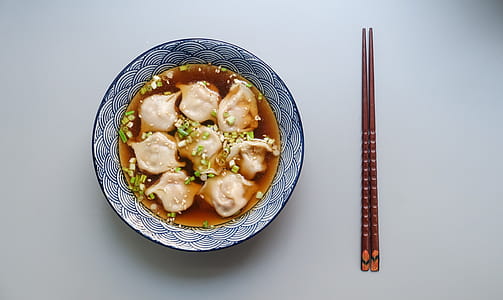 Round White and Blue Ceramic Bowl With Cooked Ball Soup and Brown Wooden Chopsticks thumbnail