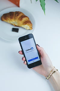 person holding black iPhone 5 displaying Linkedin application thumbnail