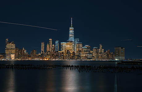 cityscape photography of lighted buildings with rocks on body of water thumbnail