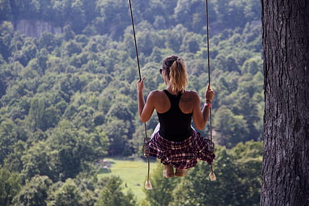 woman sits on brown swing under tree thumbnail