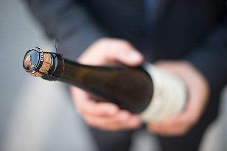 tilt shift photography of person holding wine bottle thumbnail