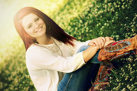smiling woman wearing white long-sleeved shirt and blue denim jeans on white flower field thumbnail