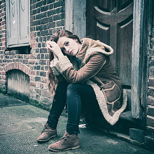 woman sitting on brown doorway touching forehead thumbnail