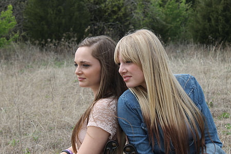 two women sitting down on brown grass field during daytime thumbnail