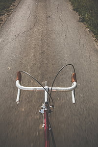 red road bike parked upright on gray concrete road thumbnail