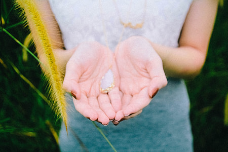 woman holding gold-colored pendant with white gemstone thumbnail