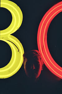 person standing near yellow and red 80 neon standee thumbnail