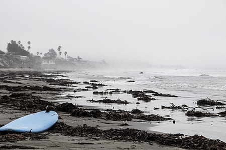 blue surfboard on sand near seashore thumbnail