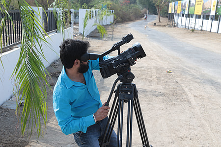 man in blue dress shirt using video camera near road thumbnail