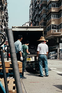 group of people looking at steel bars on truck near high-rise buildings during daytime thumbnail