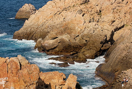 two people sitting on rocks near sea thumbnail