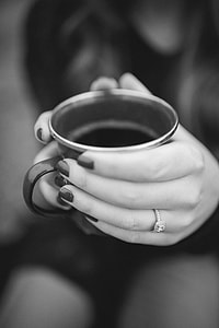 grayscale photo of woman wearing diamond ring holding ceramic cup with both hands thumbnail