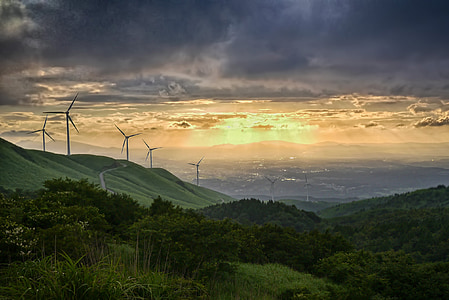 green trees near windmill under cloudy sky thumbnail