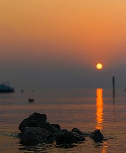 black stones on sea during sunset thumbnail
