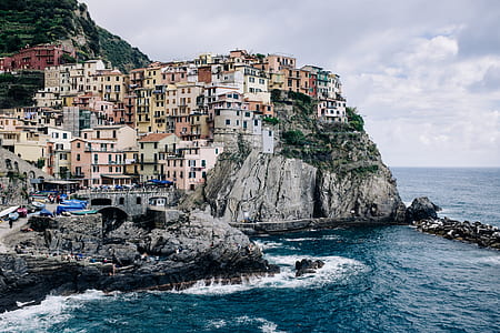 village cliff beside body of water under cloudy sky thumbnail