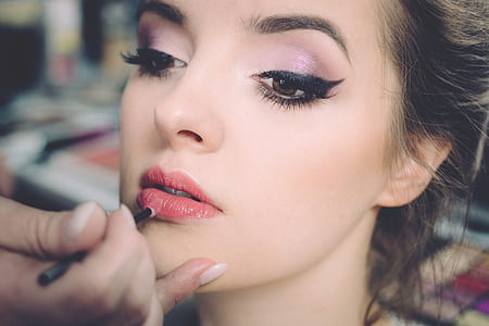person holding liquid lipstick in front of woman face thumbnail