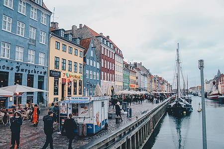 people walking in street near houses and body of water thumbnail