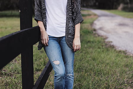person wearing black cardigan and distressed blue denim jeans thumbnail