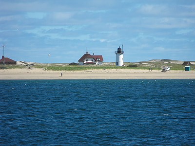 brown house near white lighthouse in front of ocean thumbnail