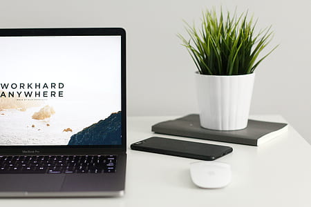 black iPhone 7 Plus beside MacBook Pro on top of white table thumbnail