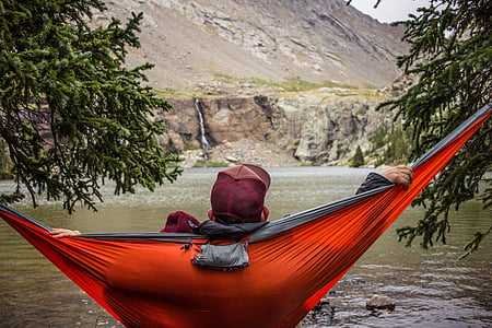 man on red hammock facing lake thumbnail