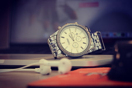 round gold-colored chronograph watch near Apple EarPods thumbnail