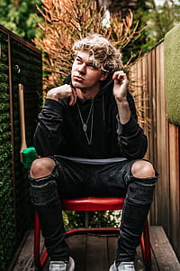 man sitting on red chair near wall thumbnail